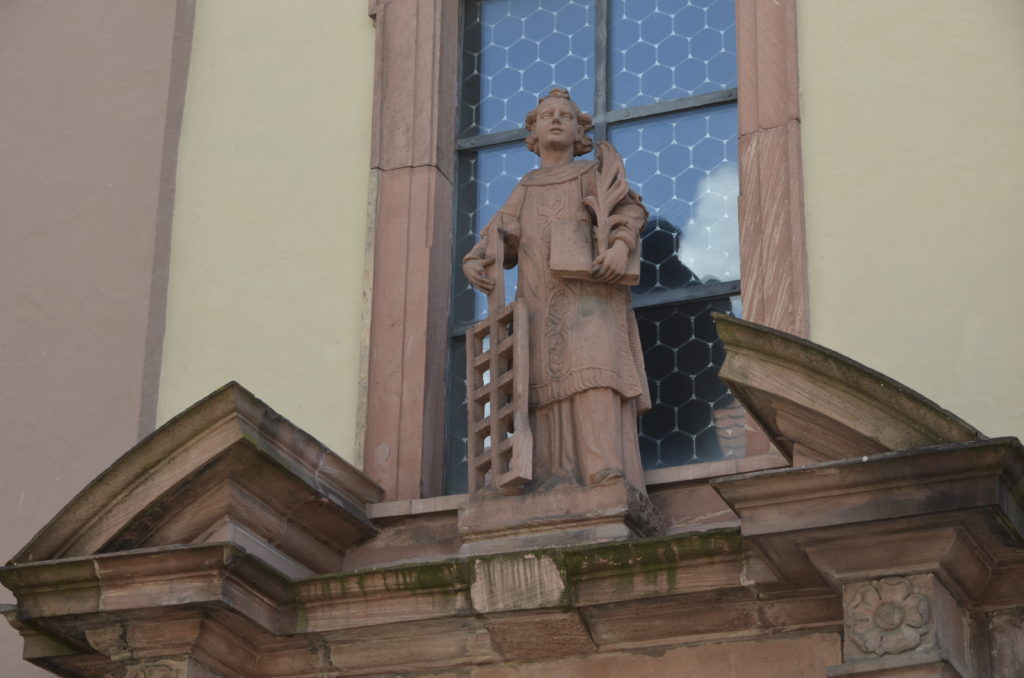 Eine Statue des heiligen Laurentius mit dem Rost krönt das Portal der zweiten Pfarrkirche in der Altstadt von Freudenberg.